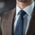 ダークブラウンのスーツに白シャツとネイビーのネクタイを合わせた、ビジネスで使えるVゾーンのコーディネート