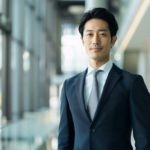 インフォーマル（平服）の指定で間違いのない、ネイビースーツとシルバーグレーネクタイを着用した大人のビジネスマンの正解スタイル