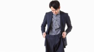 サイズが合わずダボダボなスラックスのウエストを引っ張って困る男性ビジネスマン