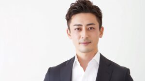 清潔感のある日本人男性が、ネイビージャケットと白シャツをノーネクタイで着用。オーダースーツSADAの店舗で相談して仕立てる、好印象でさわやかな夏のジャケパンスタイルのイメージ。40代のビジネススタイリングに最適