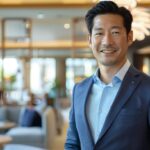 夏のジャケパンスタイル(ビジネスカジュアル)をスマートに着こなす40代役職者の男性。体にジャストフィットしたオーダーのネイビージャケットと爽やかなブルーシャツで清潔感と大人の余裕を演出